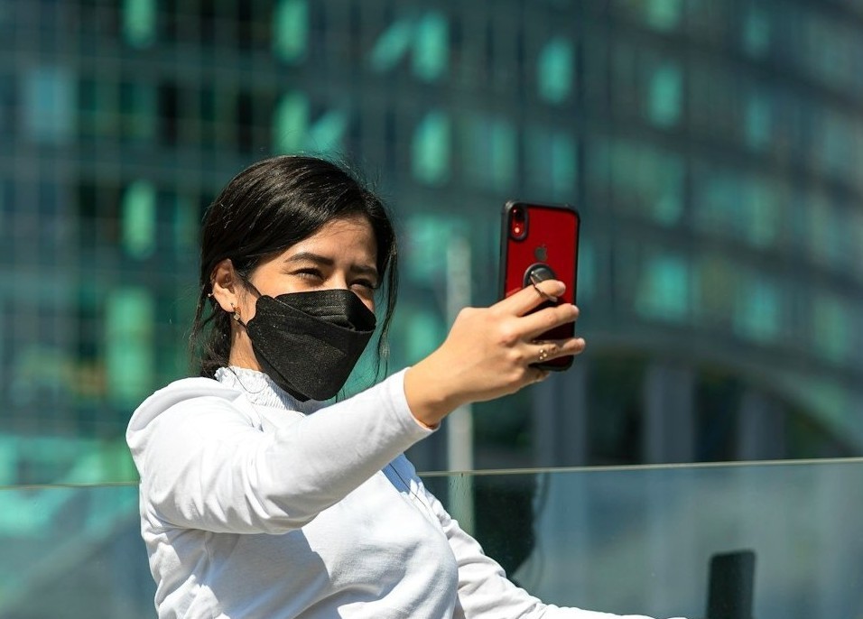 スマホリングの付いた携帯で自撮りする女性