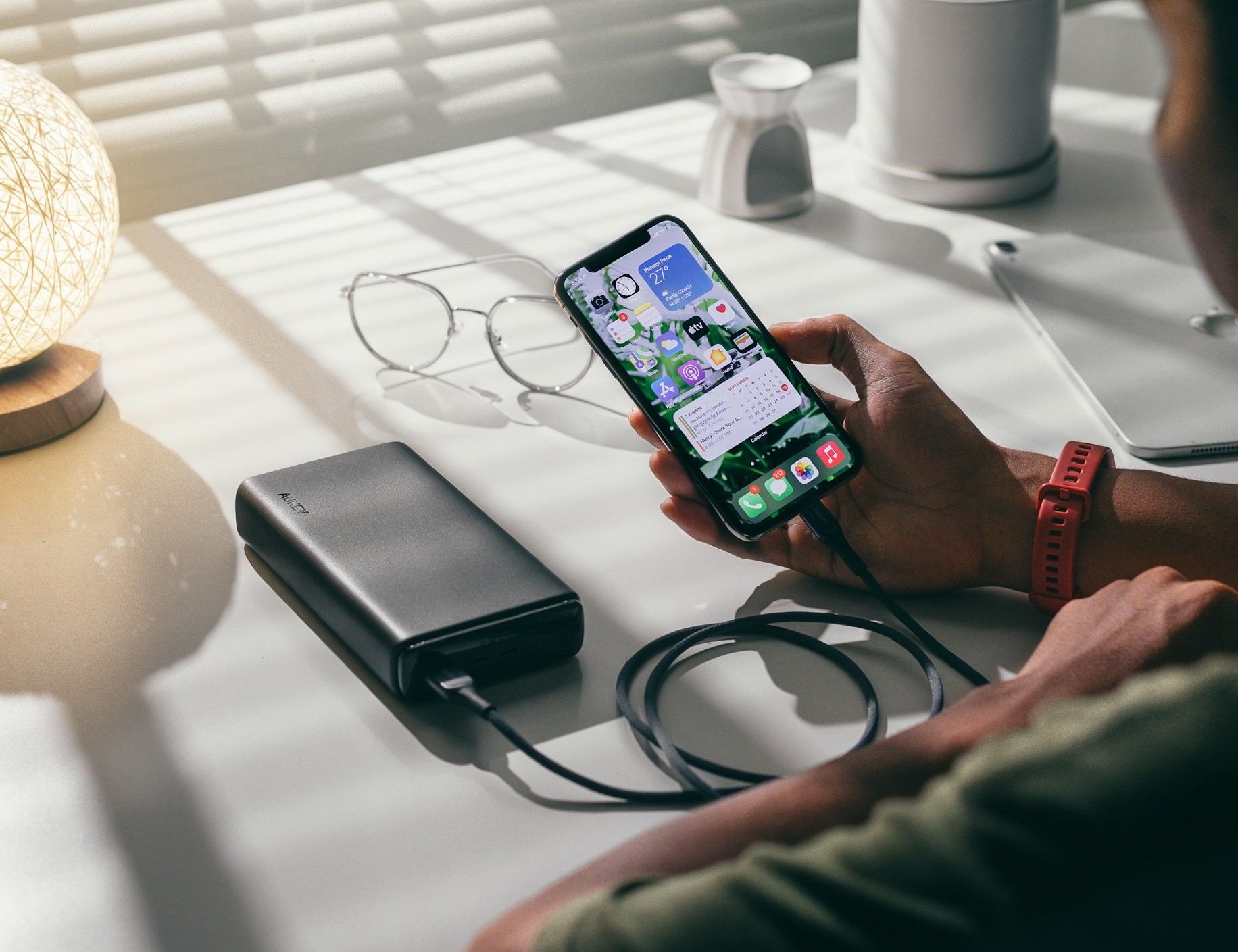 机の上で充電ケーブルを使ってスマホを充電している男性